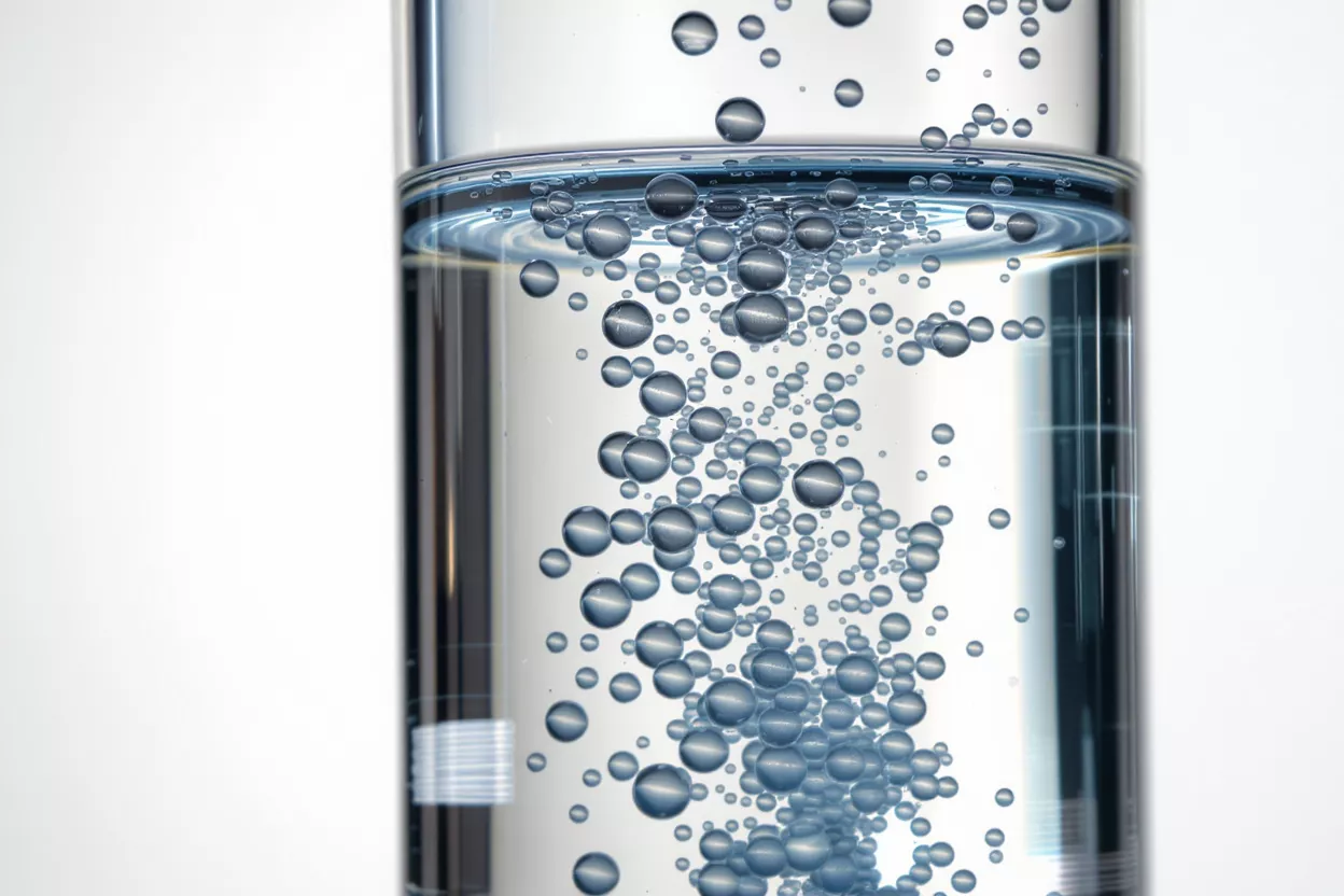 Close-up of numerous small bubbles rising in a clear glass of water.