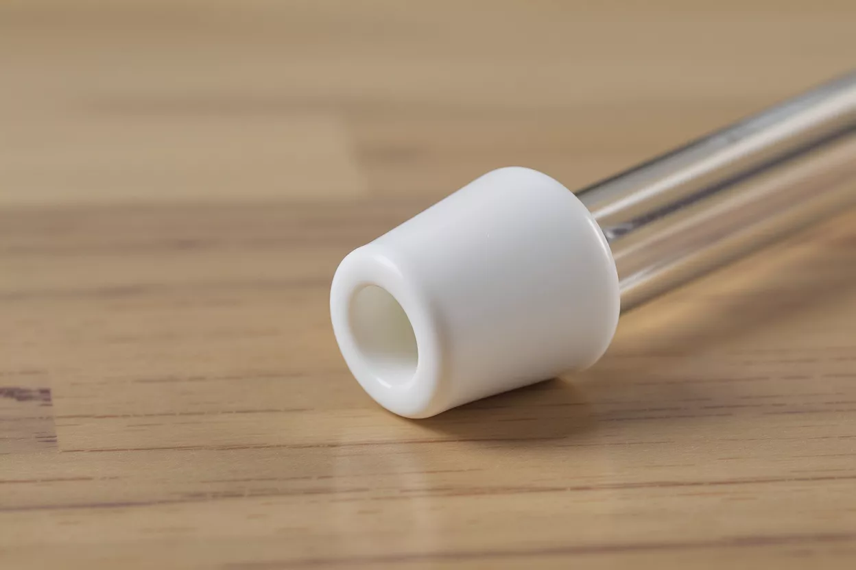 A close-up of a test tube with a white rubber stopper on a wooden surface.
