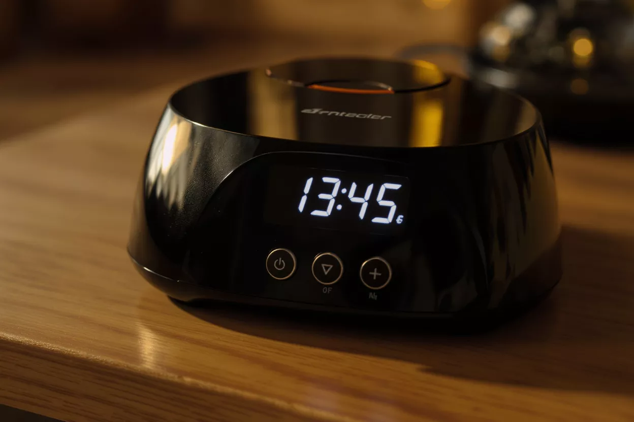 Close-up of a black digital kitchen device displaying 13:45 on a wooden surface.