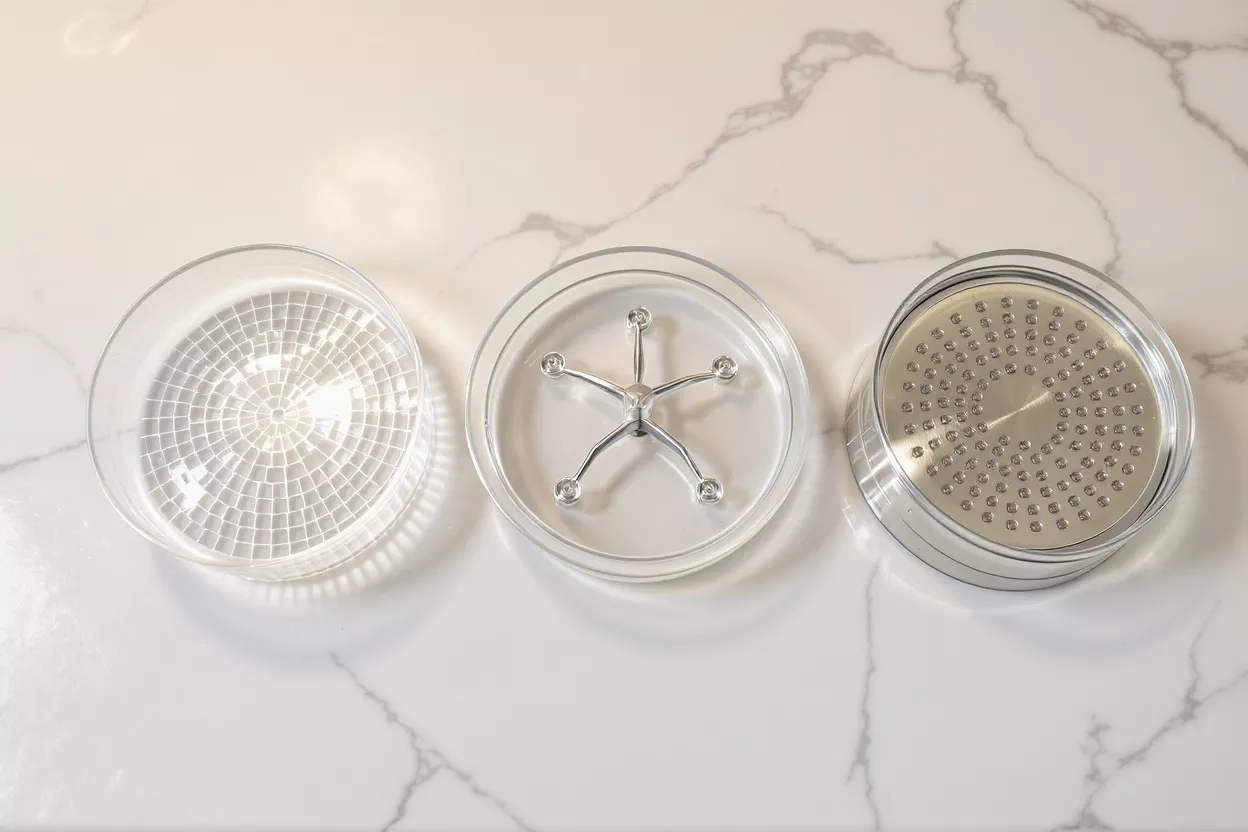 Three clear circular kitchen tools on a white marble surface, top-down view.