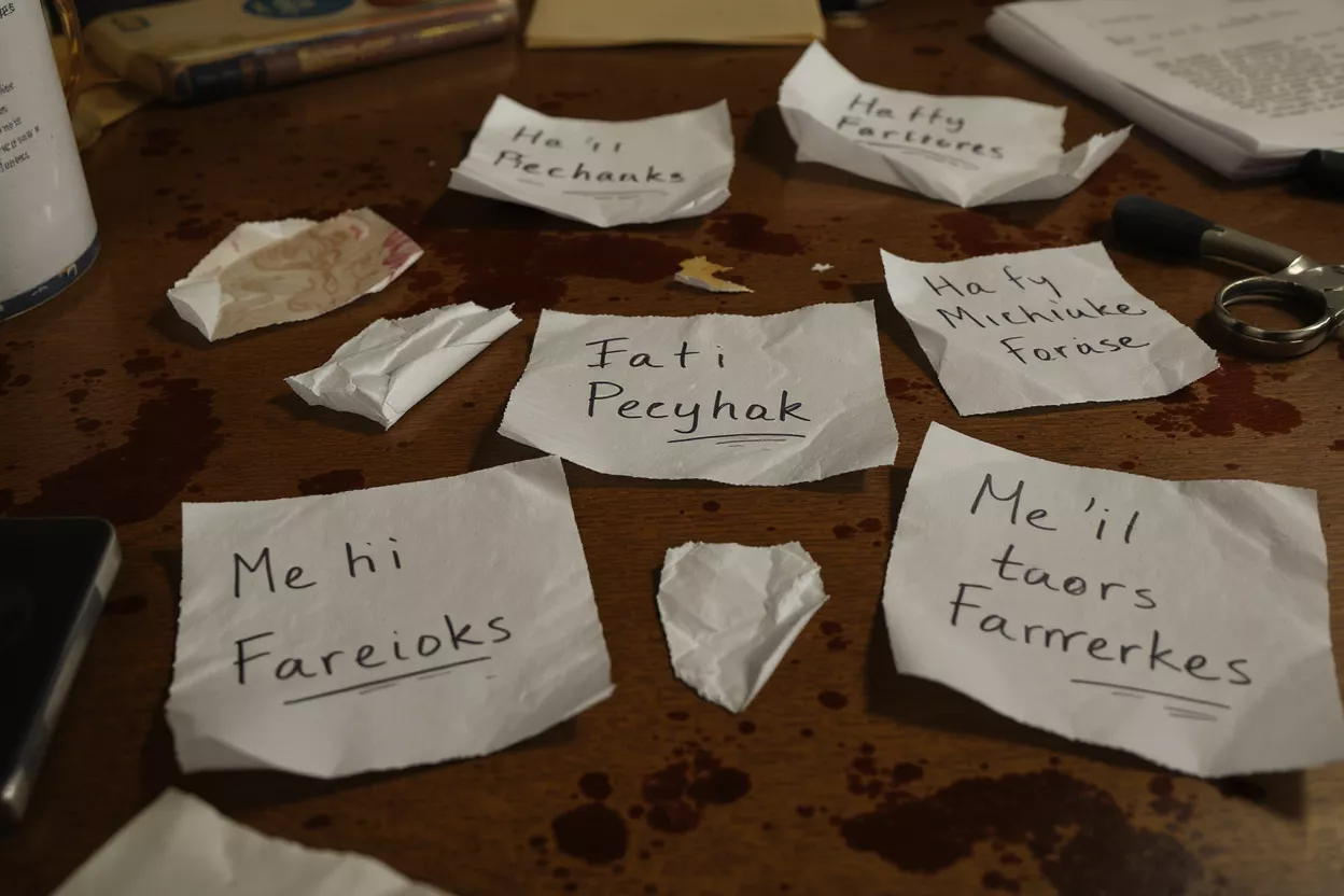 Crumpled notes with handwritten text scattered on a dark, stained wooden table.