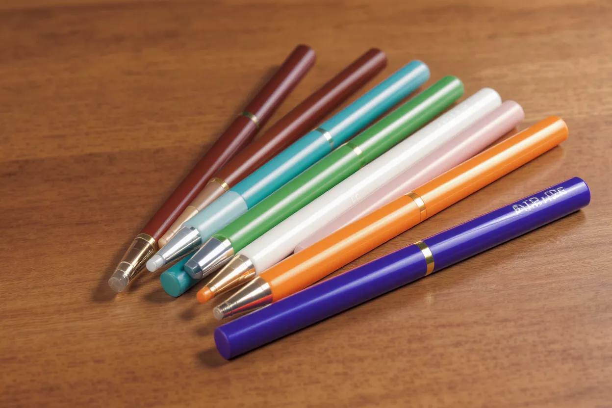 Seven colorful mechanical pencils with erasers and metal tips on a wooden desk.