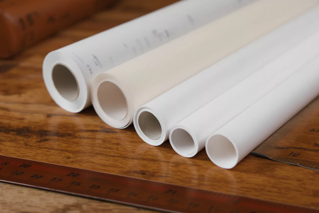 Rolls of Paper and Ruler Four rolls of paper, white and cream, on a wooden surface with a ruler.