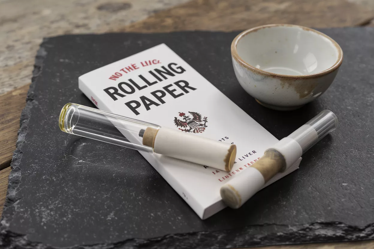 Rolling Paper Kit with Ceramic Bowl Rolling paper booklet, glass tubes, and ceramic bowl on a dark slate surface.
