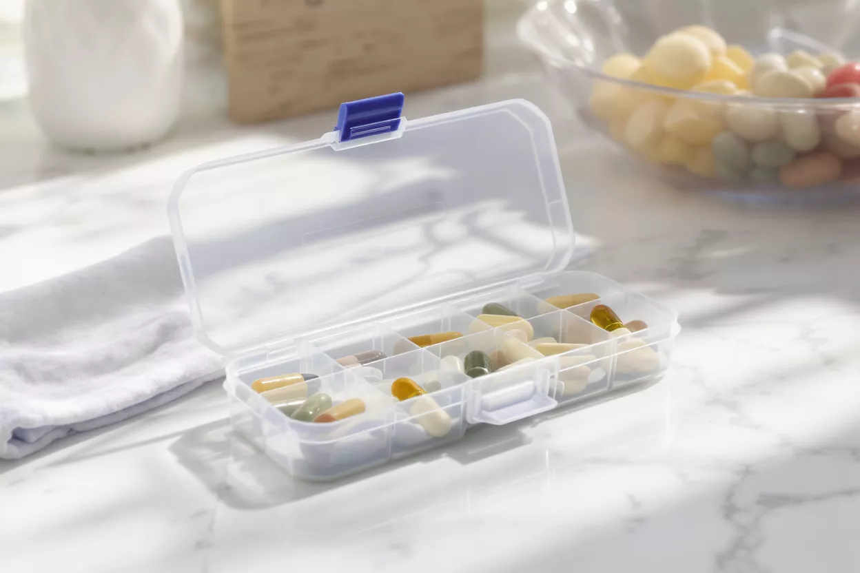 Pilulier en plastique transparent Un pilulier en plastique transparent rempli de diverses capsules colorées et de vitamines.
