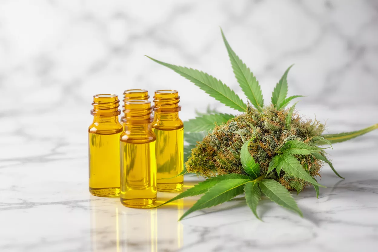 Cannabis Oil Bottles and Leaves Four amber bottles of cannabis oil with a cannabis bud