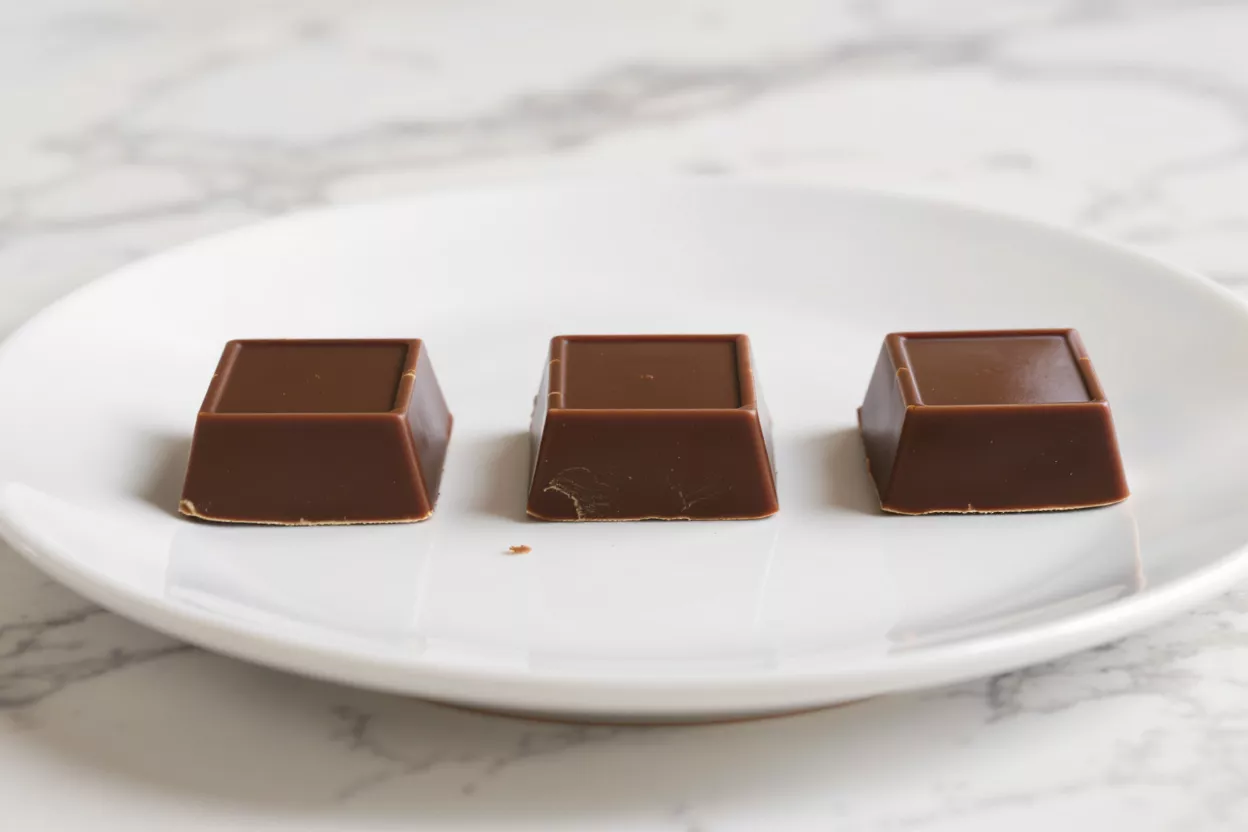 Three chocolate squares on a white plate