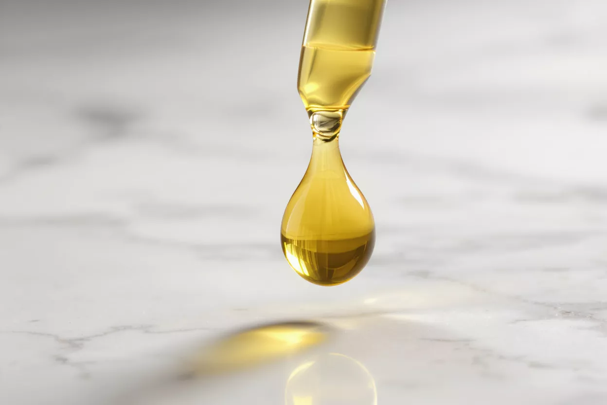Close-up of a drop of oil falling from a pipette