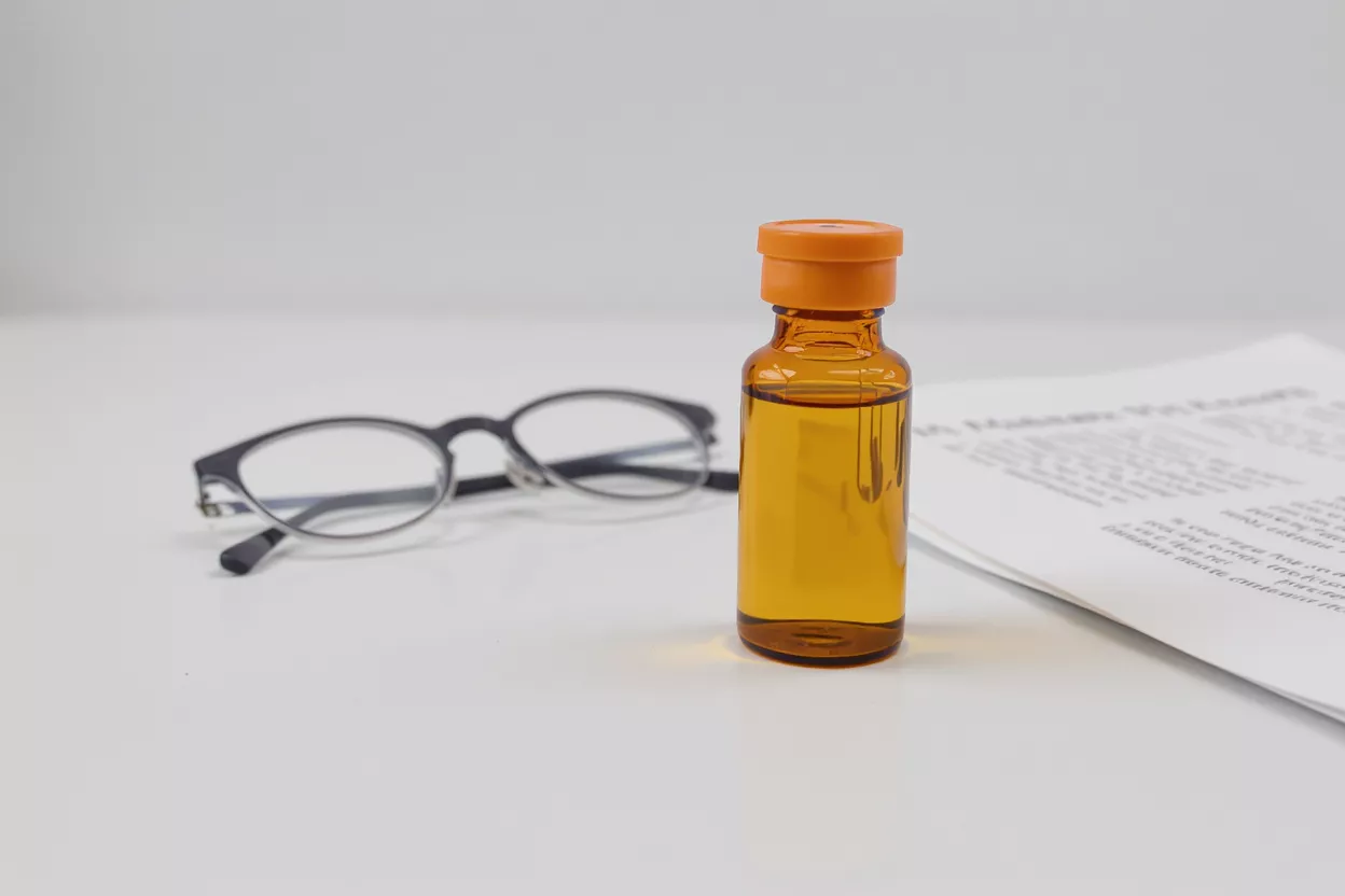 An orange bottle next to a pair of glasses