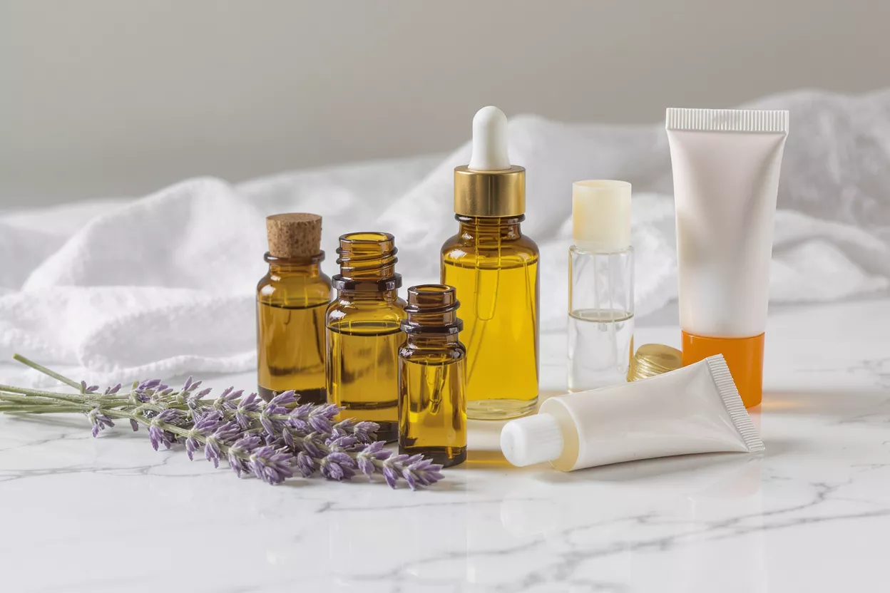 A collection of lavender essential oils and skincare products on a white marble surface.