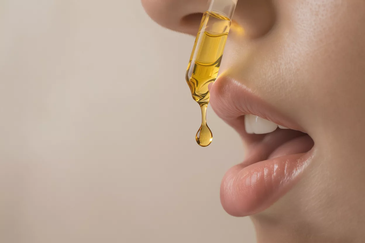 Close-up of a dropper dispensing facial oil near lips