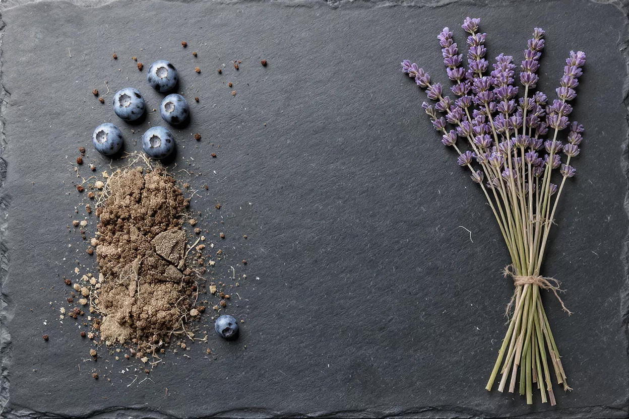 A bouquet of lavender, blueberries, and soil on a dark slate background.