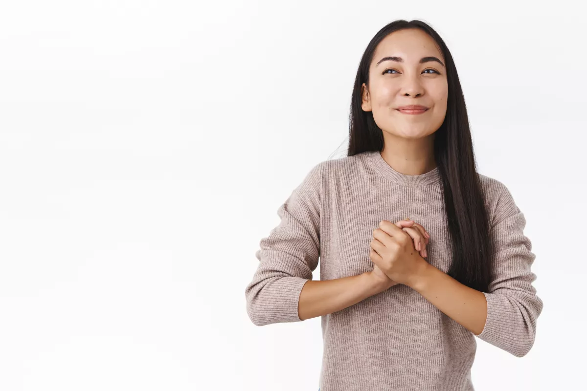Serene Asian woman in beige sweater smiling, radiating wellness and positivity.