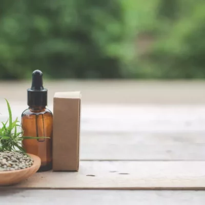 Hemp oil dropper, seeds, and plant on rustic table for natural wellness.