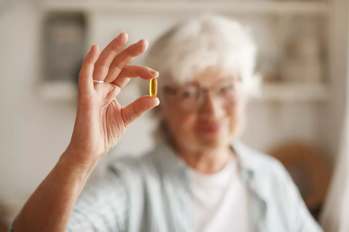 Senior woman evaluates omega-3 fish oil pill for health benefits.