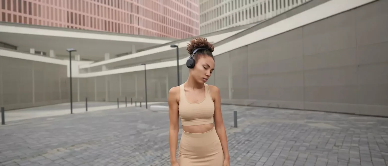 Woman with Headphones in Urban Setting Young woman with headphones and eyes closed in a modern urban environment.