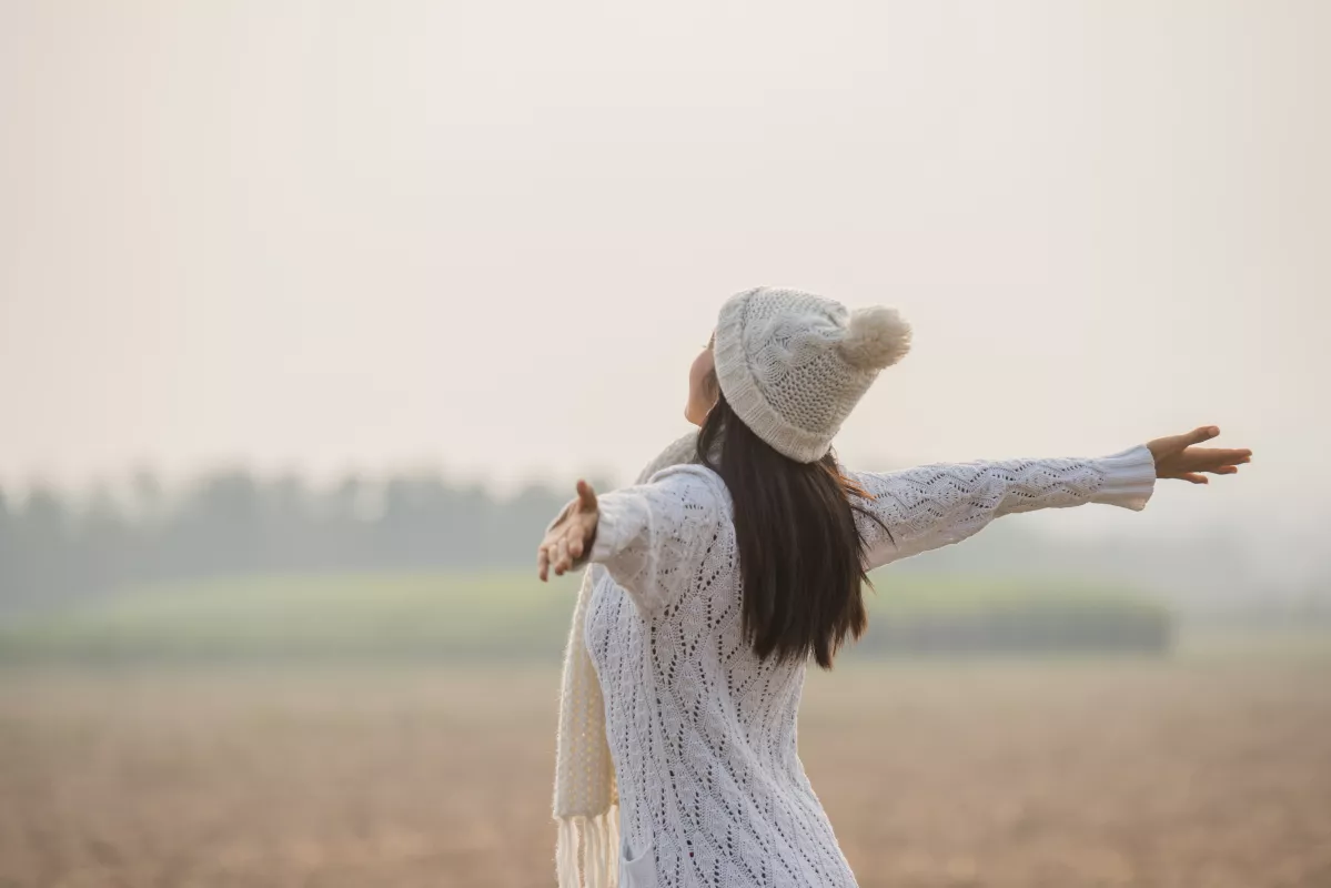 Person in white exudes peace in open field during golden hour.