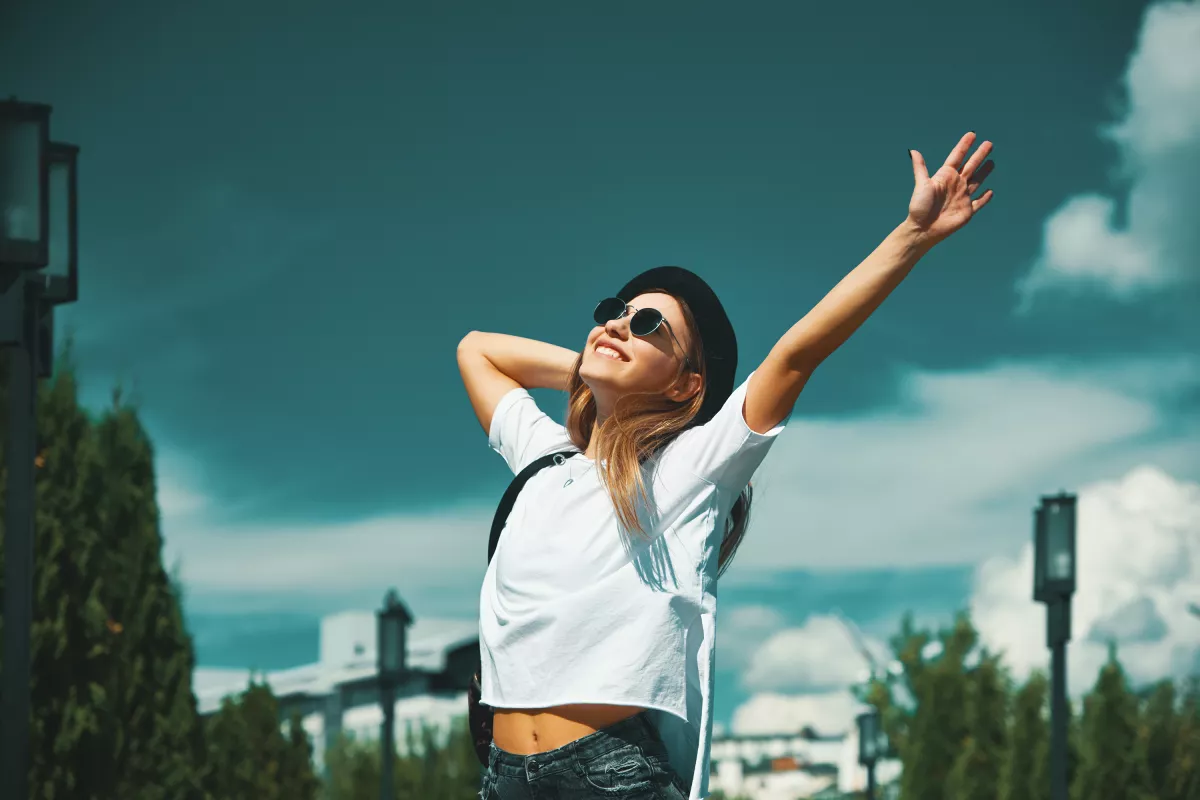 Stylish woman enjoys sunny urban day, embodying relaxation and joy.