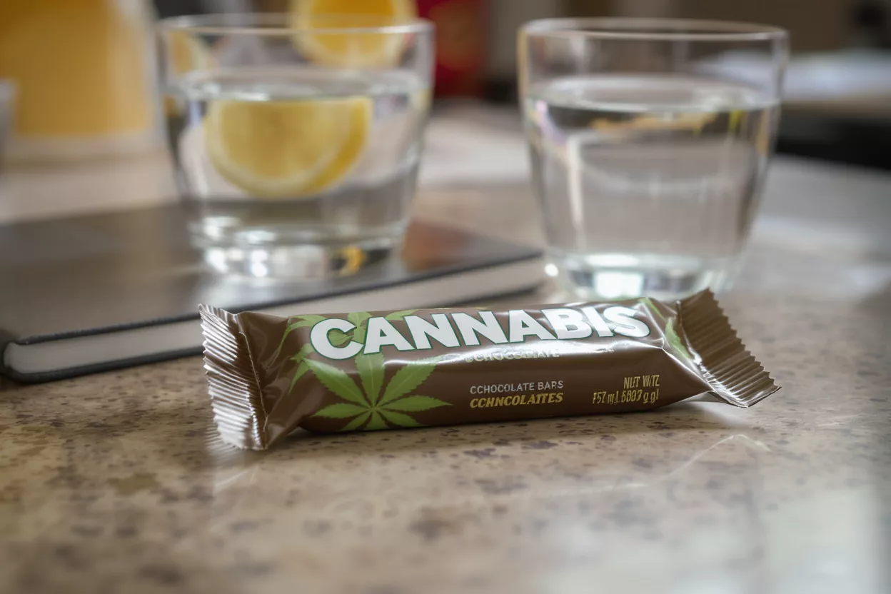 Une tablette de chocolat de marque cannabis sur un comptoir avec deux verres d'eau.
