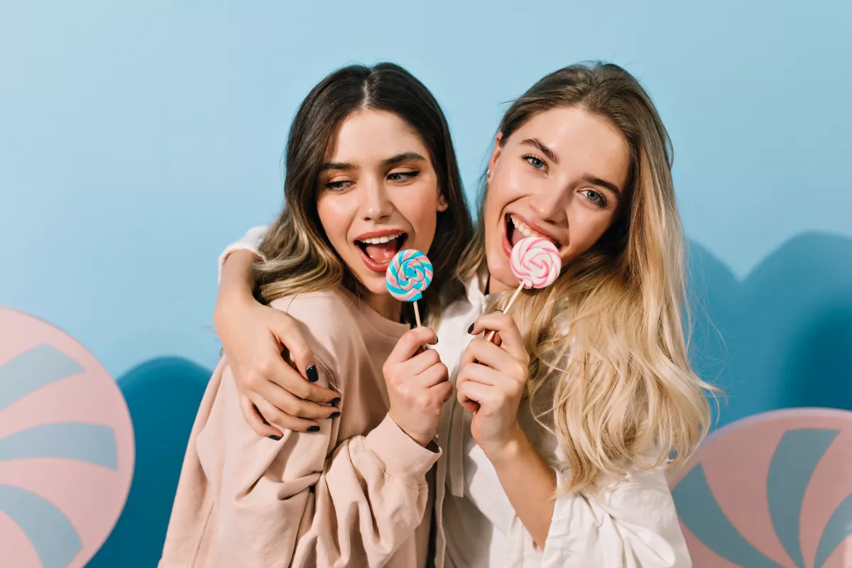 Two joyful women in candy-themed photoshoot with pastel lollipops