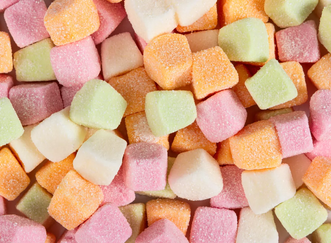 Colorful cube-shaped candies with a sugary coating in assorted fruity flavors.