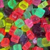 Colorful, translucent gummy candy cubes with shiny, sugary surfaces in red, green, yellow, pink, and purple.