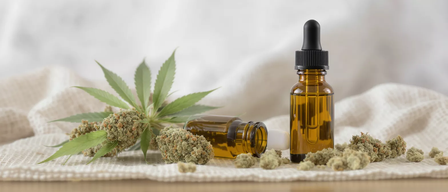 Glass bottle of cannabis oil with flowers and leaves