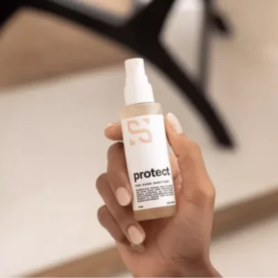 Person holding Sensitiva Protect CBD Hand Sanitizer Spray with mist nozzle and S logo.