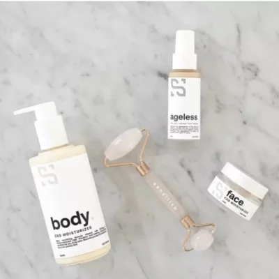 Sensitiva CBD skincare products with facial roller on marble surface.