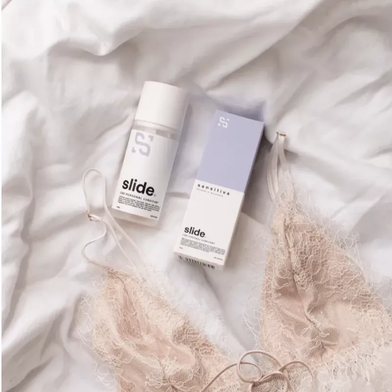 Slide lubricant and lingerie on white fabric - essentials for intimate self-care and wellness.