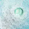 Green bath bomb dissolving in foamy, bubbly water.