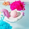 Unicorn tray with bath bomb, pink and blue poufs, toy pig in clear water.