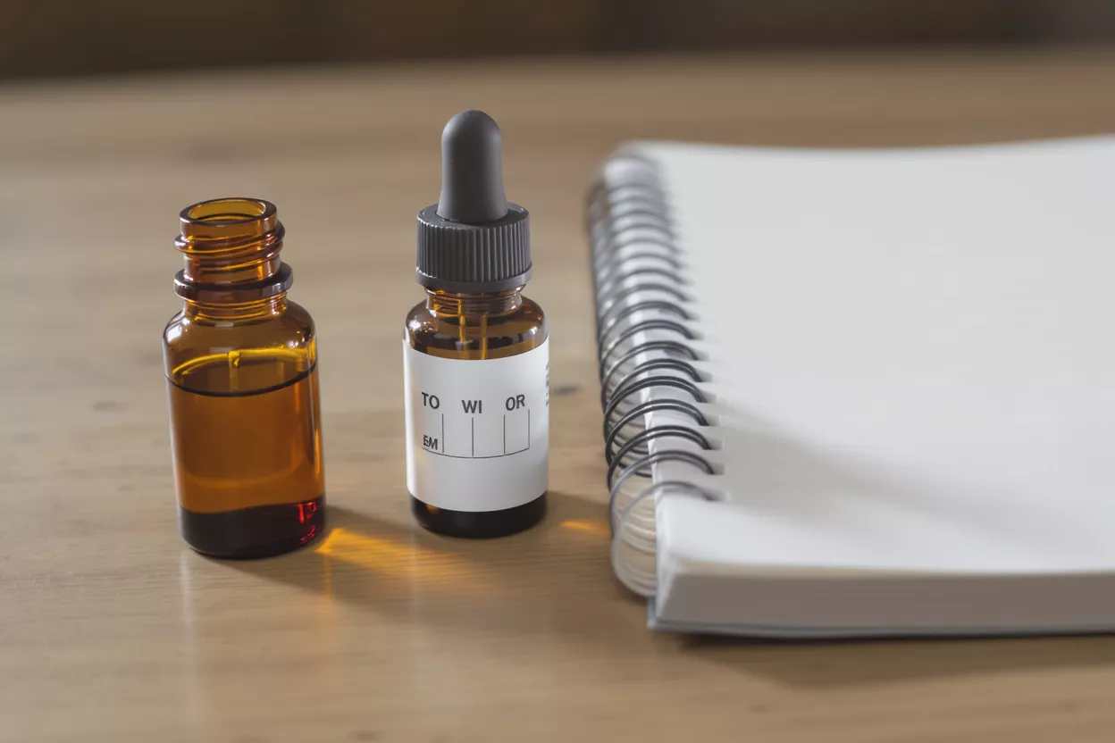 Two amber glass bottles, one with a dropper, next to a spiral notebook.