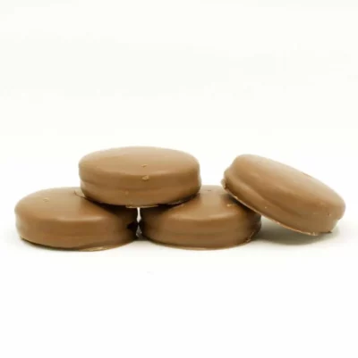 Five glossy milk chocolate confections with smooth tops displayed on a white background.