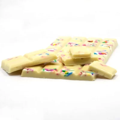 White chocolate bar with colorful sprinkles, broken into festive pieces for a birthday celebration treat.