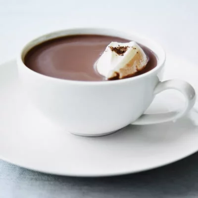 Creamy hot chocolate with whipped cream in a white cup, perfect cozy drink.