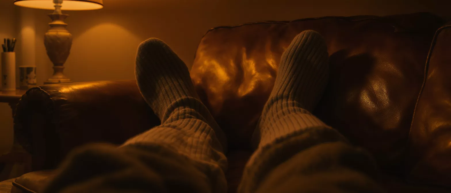 Person's feet in cozy socks on a leather couch