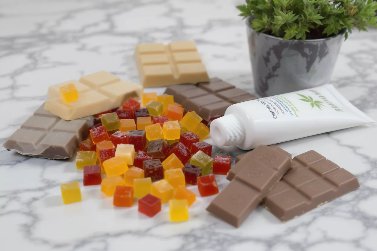 CBD Edibles and Topical CBD gummies, chocolate bars, and topical cream on a marble surface.