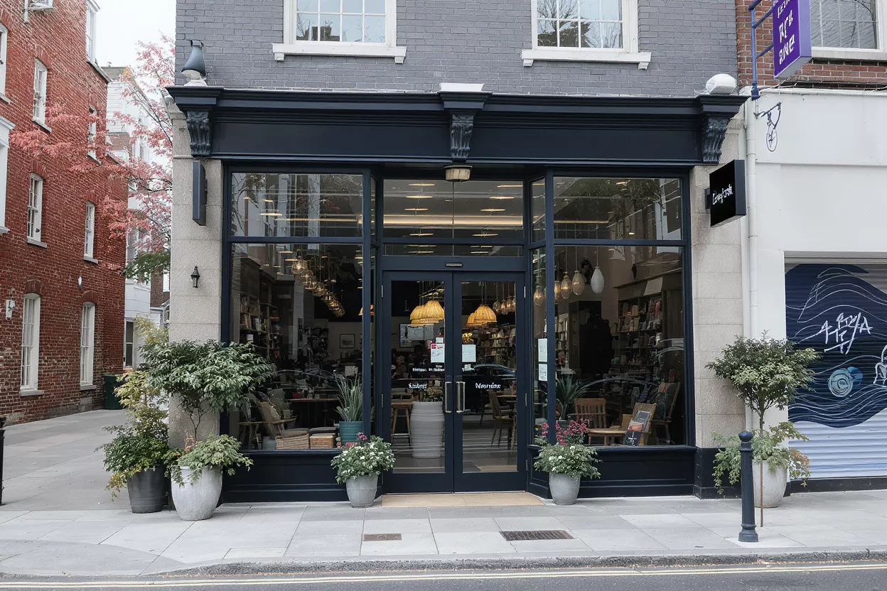 Charming Storefront on a City Street A stylish storefront with large glass windows and potted plants on a city street.