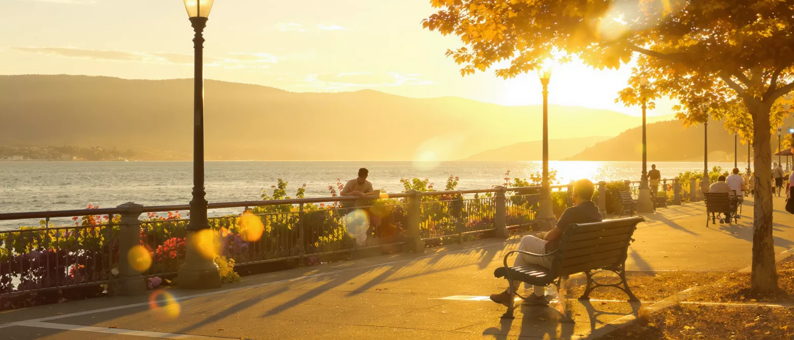 People enjoying a golden sunset over a lake with mountains in the background.