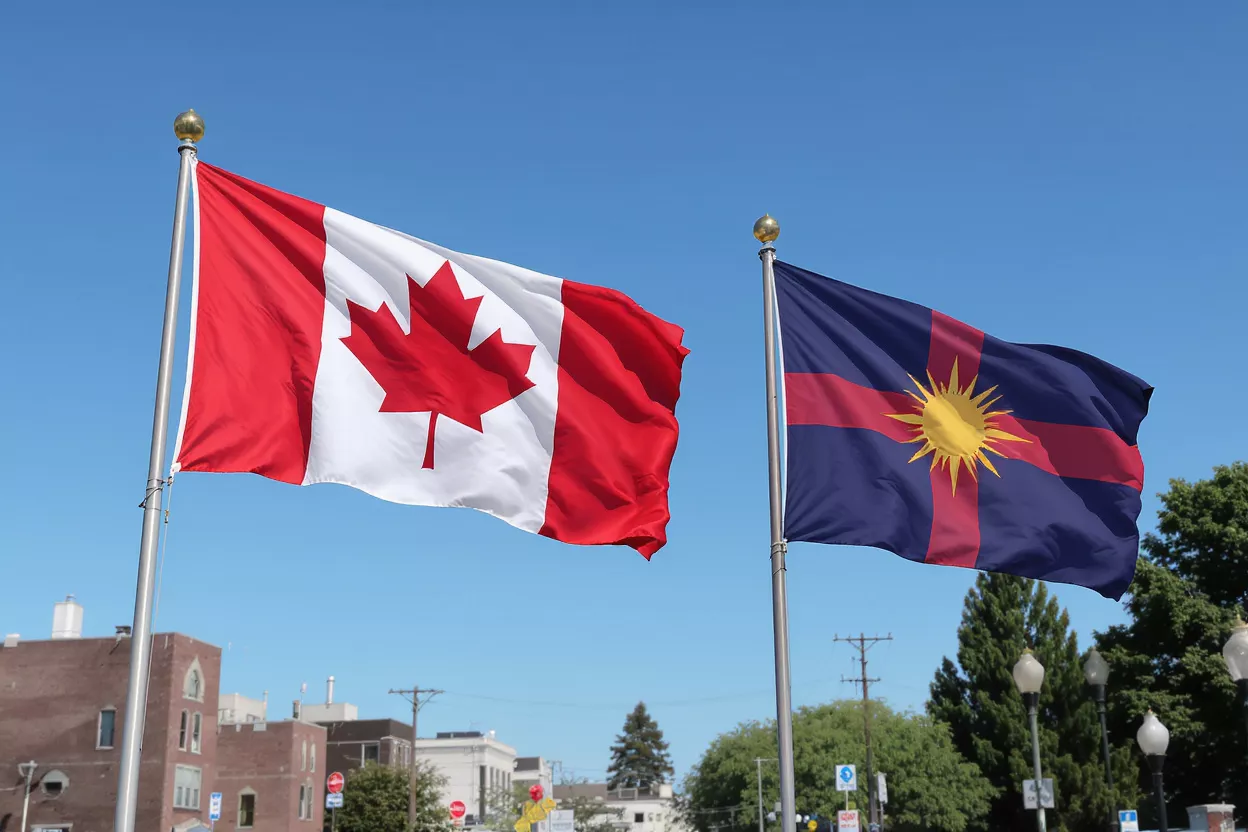 Canadian and Malaysian flags flying side-by-side against a clear blue sky.