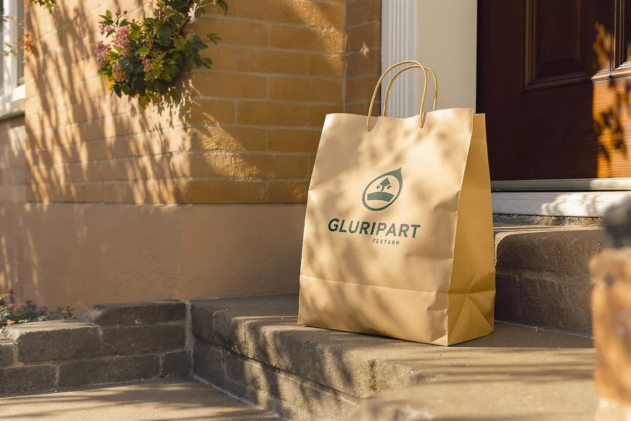 Gluripart Delivery Bag A brown paper Gluripart delivery bag sits on a doorstep in sunlight.