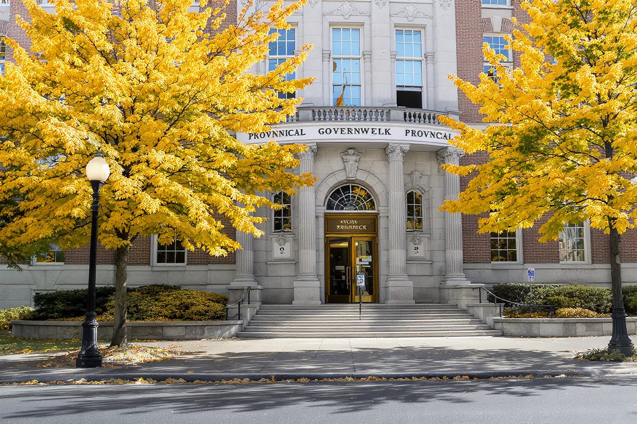 Historic building with golden autumn trees flanking the entrance and steps.