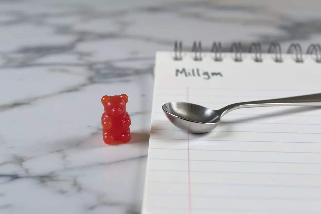 A pile of red, orange, and white sugar-coated gummy cubes on a marble surface.