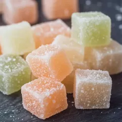 Colorful sugar-coated gummy cubes on dark background.