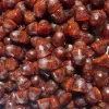 Close-up of glossy, dark brown, barrel-shaped candies, resembling acorns, evoking caramel or coffee flavors.
