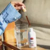 Person adding Reishi mushroom tincture to water for wellness benefits in a cozy setting.