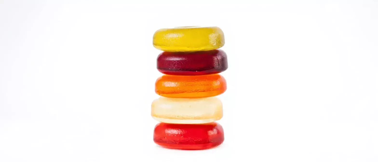 Five round, colorful gummy candies stacked vertically on a white background.