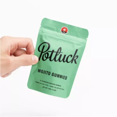 Hand holding Potluck Mojito Cannabis Gummies with THC/CBD content against white background.
