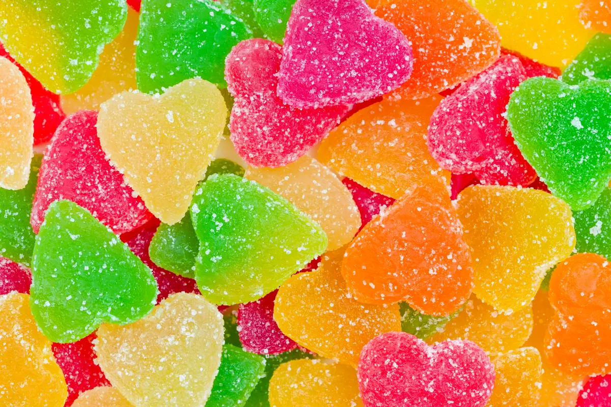 Colorful sugar-coated heart gummies suggestive of fruity flavors.